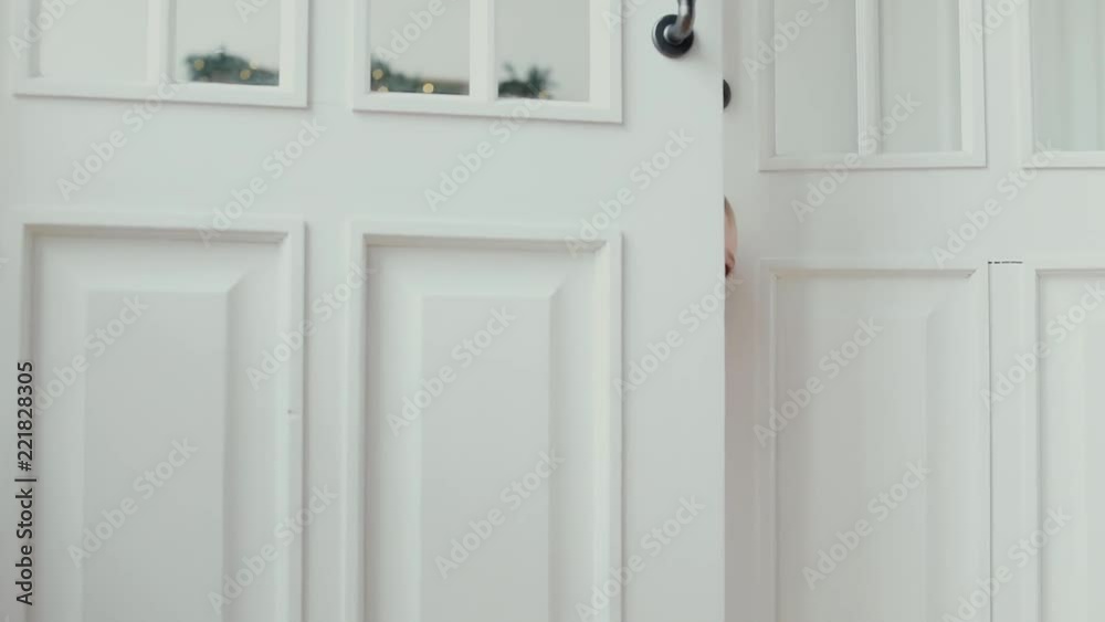 Baby boy peeking out of the open white room door Baby boy peeking out of the open white room door