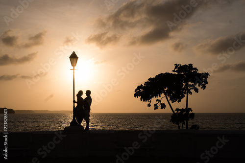 Silhouette of a couple in a lamp over a wall at sunset in Sao Luis do Maranhao.
