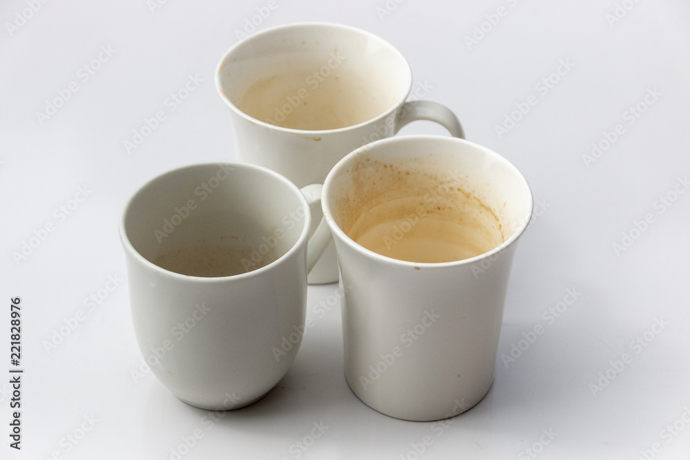 A Close up side view of three dirty white coffee mugs in a group on a isolated white background A Close up side view of three dirty white coffee mugs in a group on a isolated white background