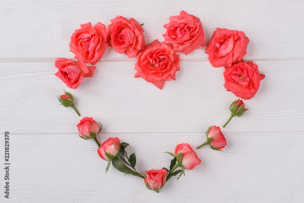 Heart shaped rose flowers composition. White wooden background. Top view. Heart shaped rose flowers composition. White wooden background. Top view.