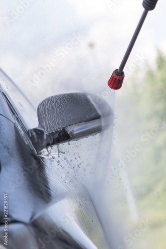 Fototapeta Naklejka Na Ścianę i Meble -  Mann nutz  Hochdruckstrahler mit Wasser um Reinigungsmittel  bei Autowäsche in Auto SB Waschbox abwaschen