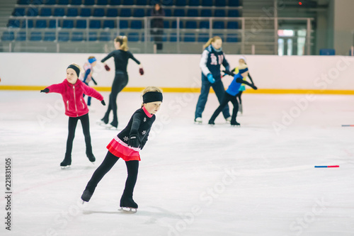 Little girls learning to ice skate. Figure skating school. Young figure skaters practicing at indoor skating rink.