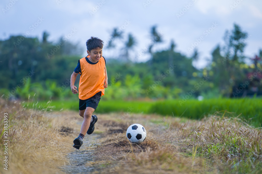 8 or 9 years old happy and excited kid playing football outdoors in garden  wearing training vest running and kicking soccer ball Photos | Adobe Stock