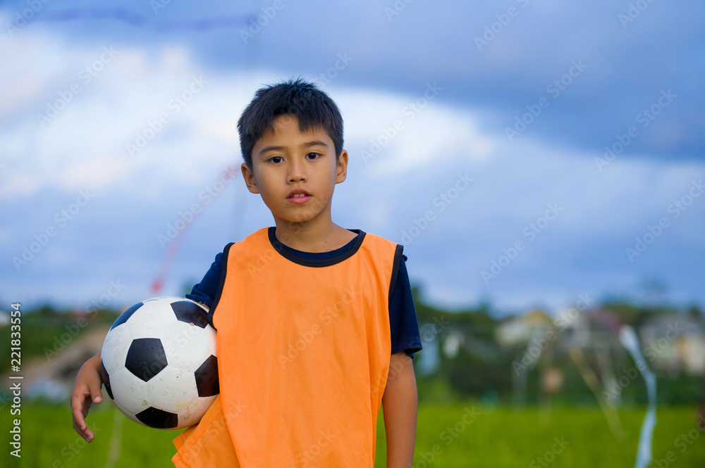 lifestyle portrait of handsome and happy young boy holding soccer ball ...