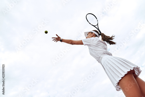 Rear view of tennis woman player serving during a game © Friends Stock