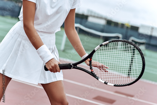 Close up of a young woman ready to hit a tennis ball, serving a ball during game.