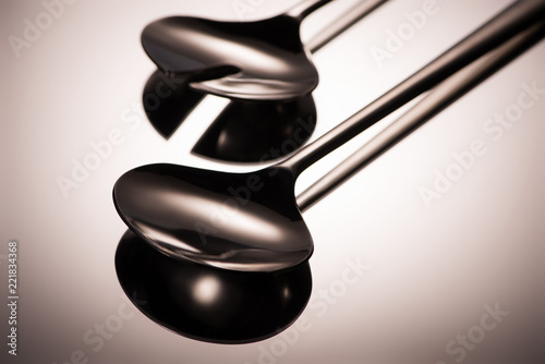 close-up view of shiny stainless steel ladles reflected on grey