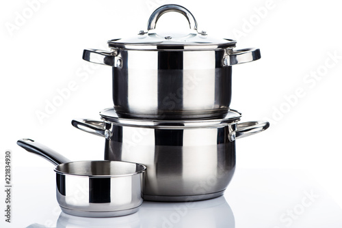 close-up view of shiny stainless steel pots and pans on white photo