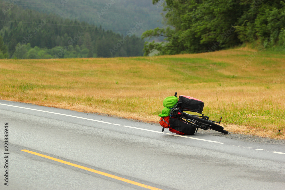 Bicycle with touring bags lying on a roadside Bicycle with touring bags lying on a roadside