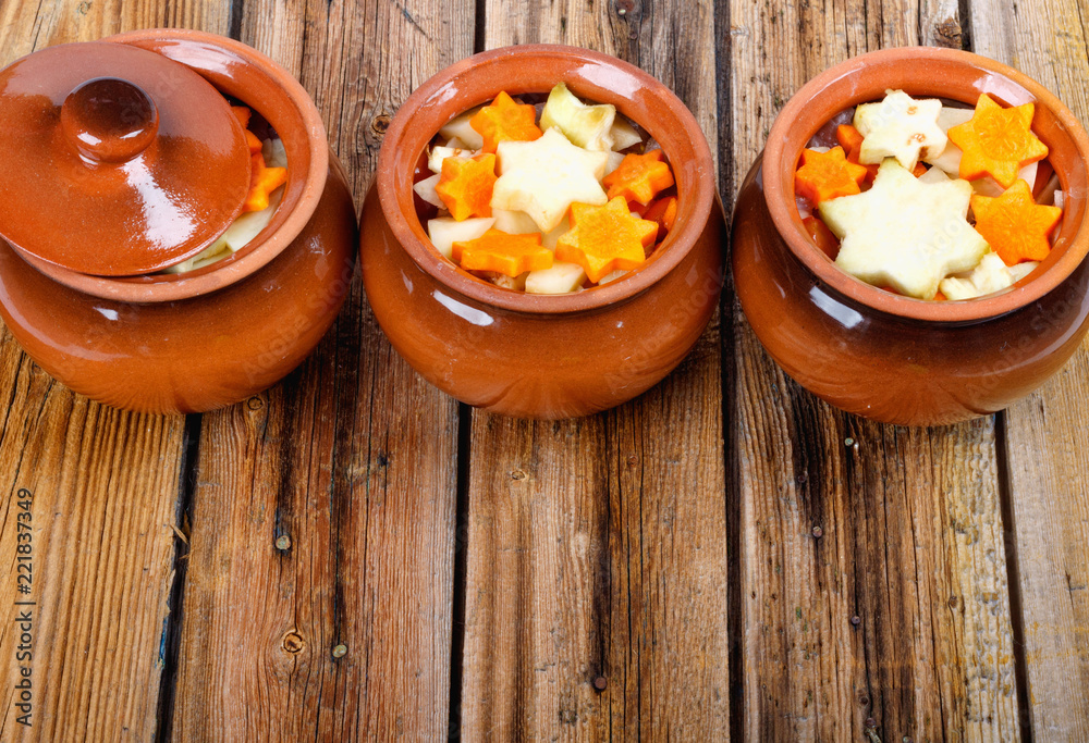 Fototapeta premium Traditional rustic home vegetable stew in three clay pots on old vintage wooden table.
