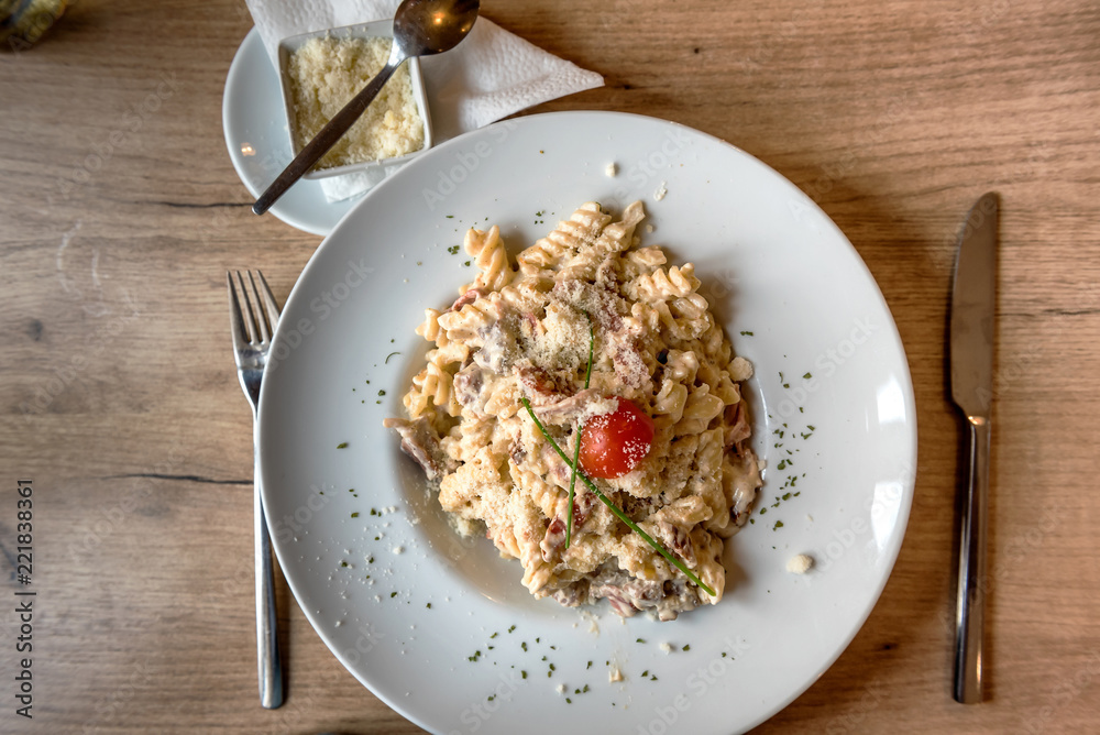 Colorful plate with penne pasta with prosciutto and spinach on a table