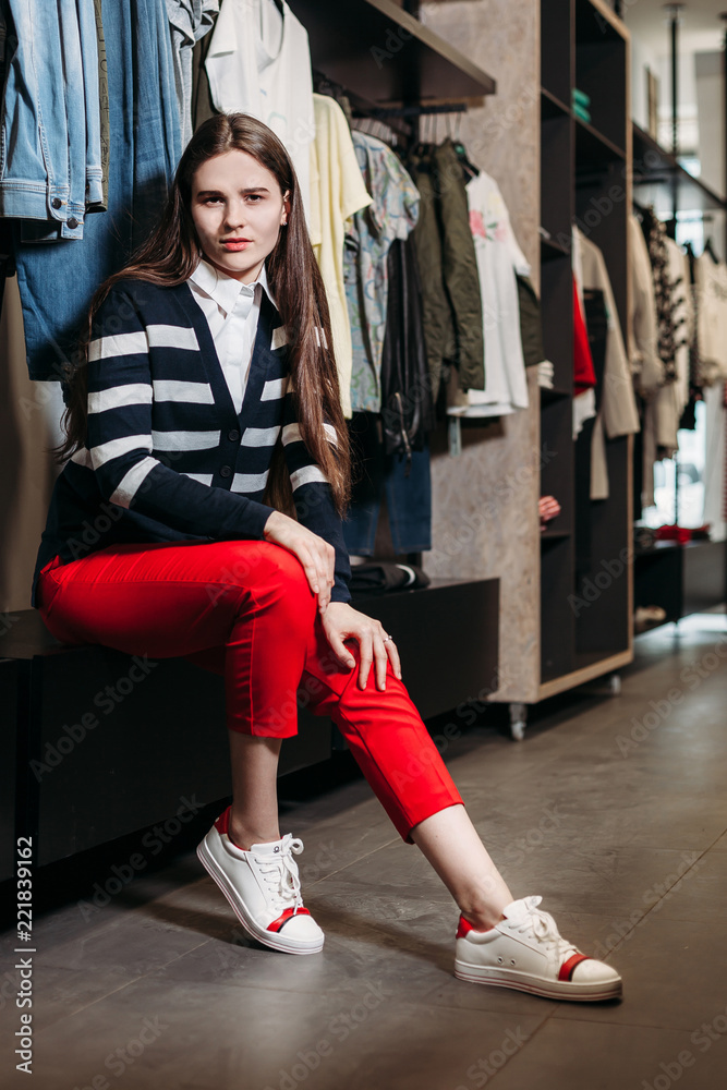 Obraz premium Beautiful model brunette girl posing in clothing store, a new trend of clothes. Banner for a clothing store. For showrooms and fashion stores, cover stories, interior studio
