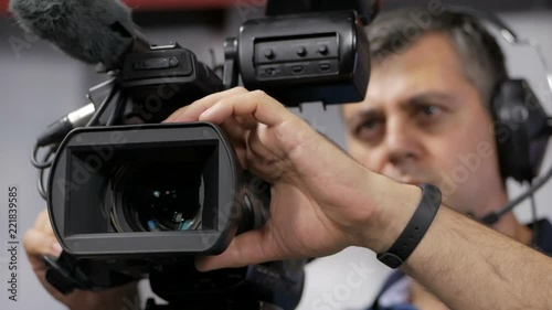 The cameraman is working behind the camera.