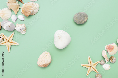 Flat lay. Top view. Frame of shells of various kinds on a green blue background. Seashells and starfish on a pastel background. Vacation concept