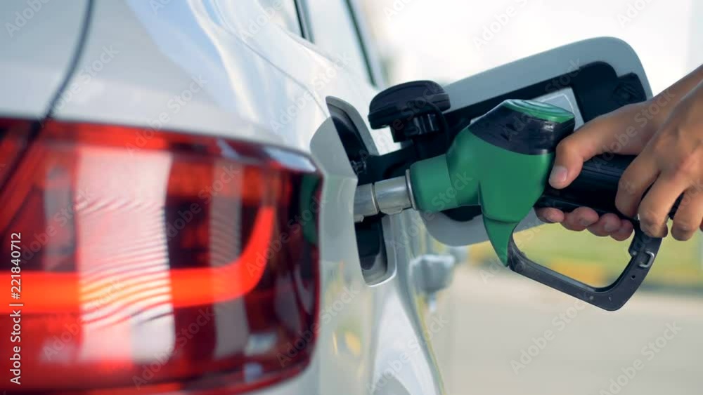 Fuel nozzle is getting inserted into automobile's tank. Fuel, gas station, petrol prices concept.