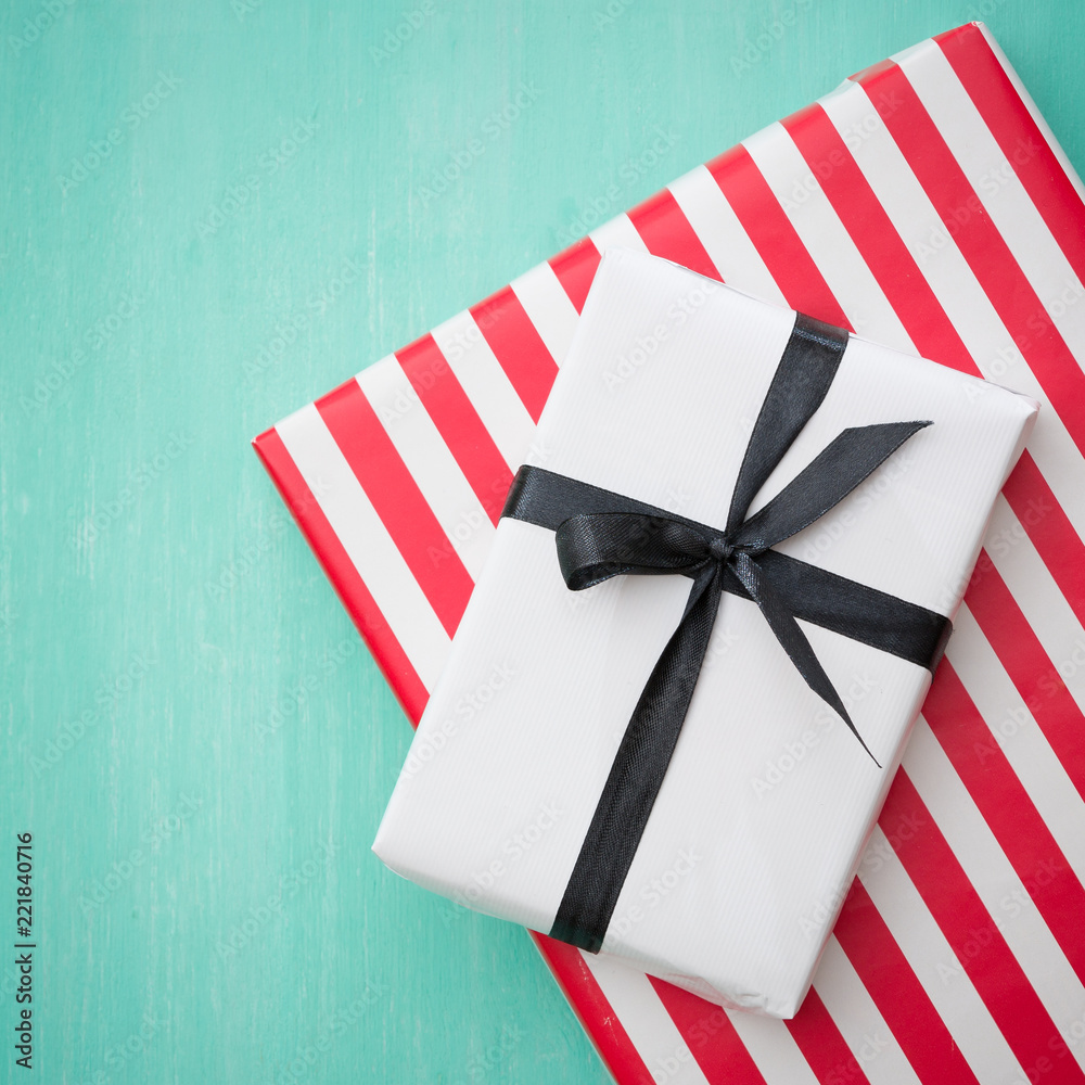 Closeup of beautiful Christmas gifts wrapped in white and striped gift paper decorated with ribbon on turquoise wooden table. New Year, holidays and celebration concept Closeup of beautiful Christmas gifts wrapped in white and striped gift paper decorated with ribbon on turquoise wooden table. New Year, holidays and celebration concept