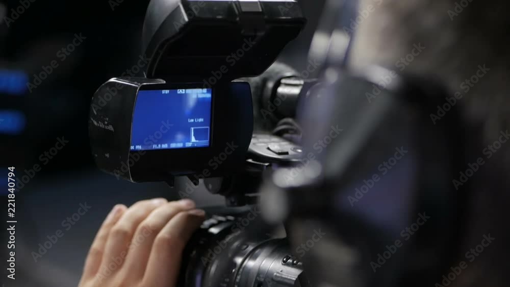The cameraman is working behind the camera.