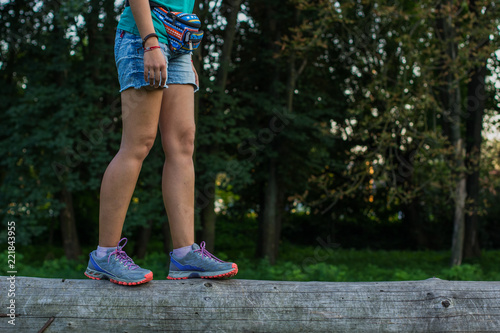 person step concept shot of female bare  feet in sneakers on wooden deck object in outdoor unfocused natural park environment with empty copy space for your text