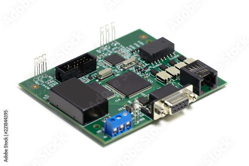 Electronic printed circuit board with chips and other components, green color, front side, angled view, isolated on white background