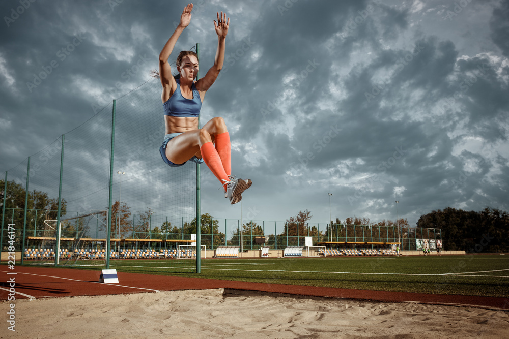 Female athlete performing a long jump during a competition at stadium ...