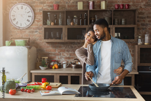 Happy couple embracing while cooking in kitchen
