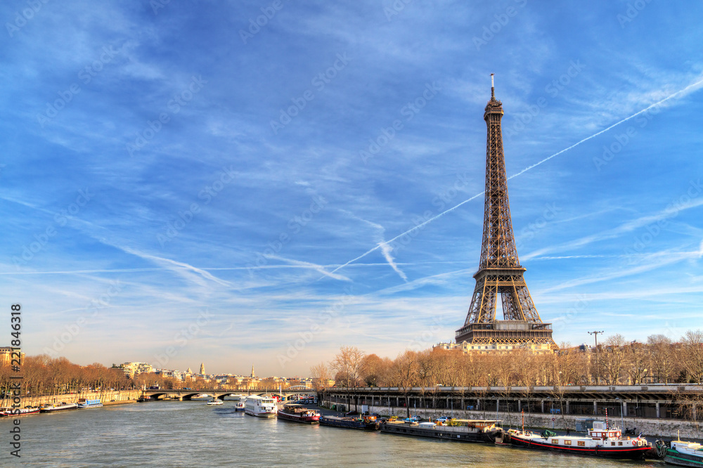 Fototapeta premium Beautiful Eiffel tower at the Seine river with a dramatic sky in winter
