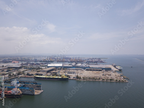 Aerial view of logistics concept floating dry dock servicing cargo ship and commercial vehicles, cars and pickup trucks waiting to be load on to a roll-on/roll-off car carrier ship at Laem Chabang 