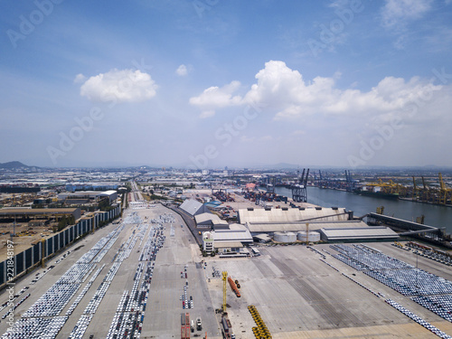 Aerial view of logistics concept floating dry dock servicing cargo ship and commercial vehicles, cars and pickup trucks waiting to be load on to a roll-on/roll-off car carrier ship at Laem Chabang 