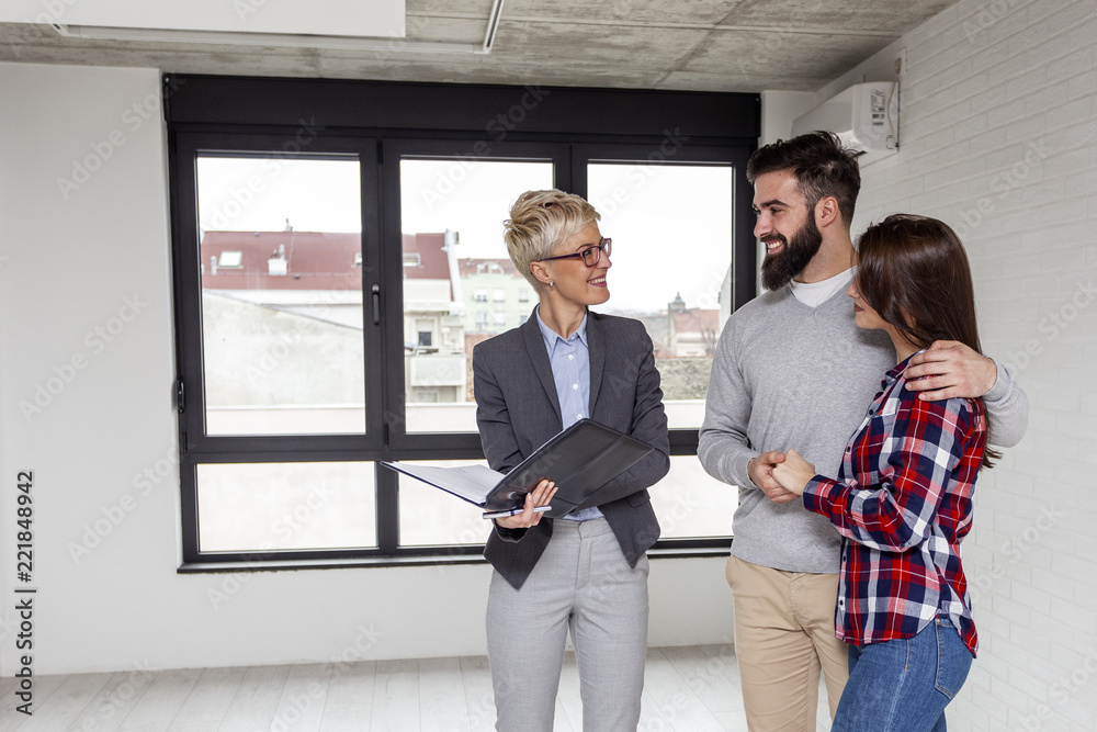 Real estate agent showing a new appartmen to young couple who want to buy it Real estate agent showing a new appartmen to young couple who want to buy it