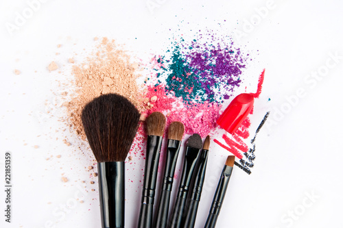 Makeup brushes on white background with colorful powder. Make-up background.