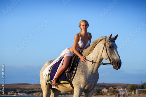 beautiful young woman on a horse near the sea
