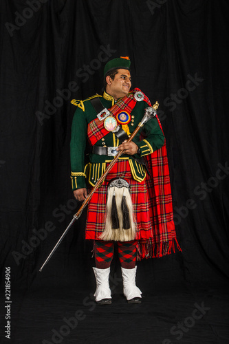 A portrait of an Indian American Scottish drum major smiling and looking away from camera in full Scottish regalia, including kilt and sporrans