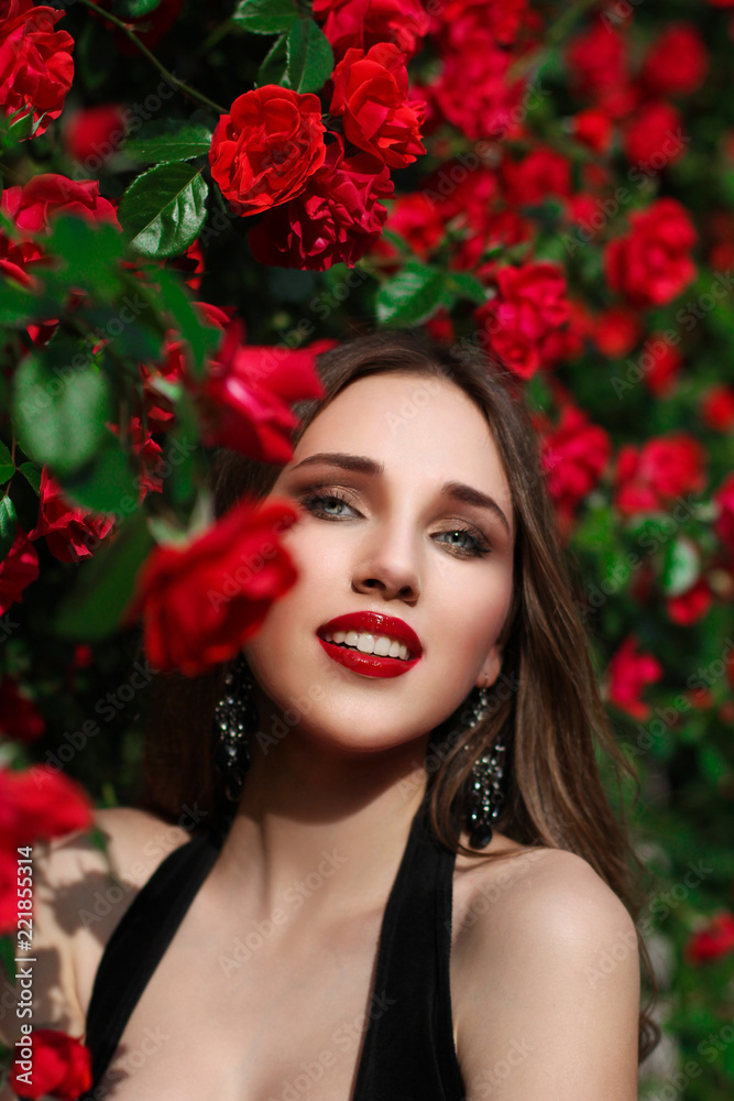 Fototapeta premium Portrait of beautiful young woman in the rose garden, spring time, rose flowers blossoms.