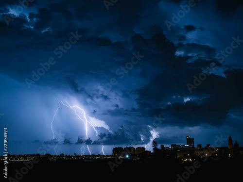 Fondo con cielo nocturno con nubes de tormenta, rayos y relampagos en tonos azulados.Noche de Tormenta con rayos sobre los edificios, en Valencia, España. 10 de septiembre de 2018