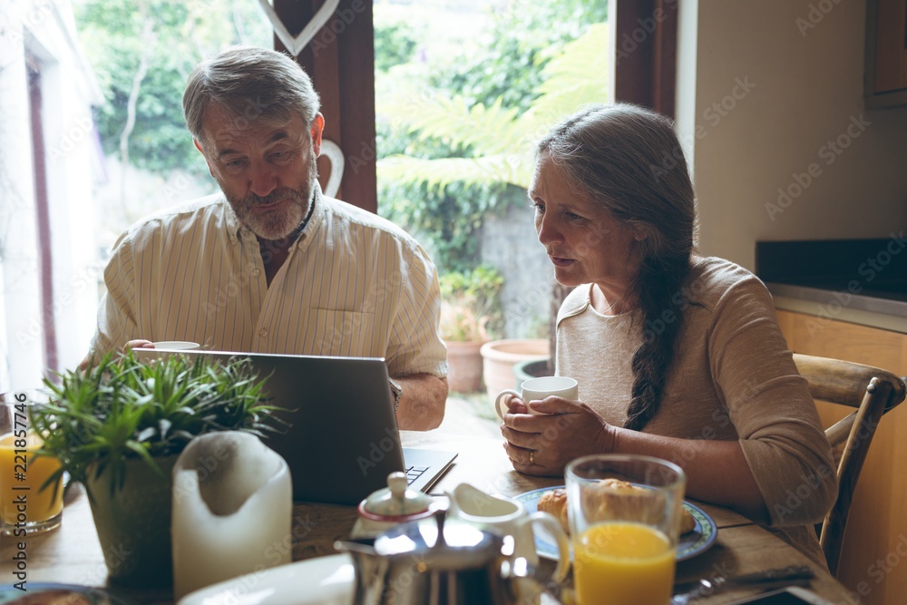 Senior couple using laptop while having coffee Senior couple using laptop while having coffee