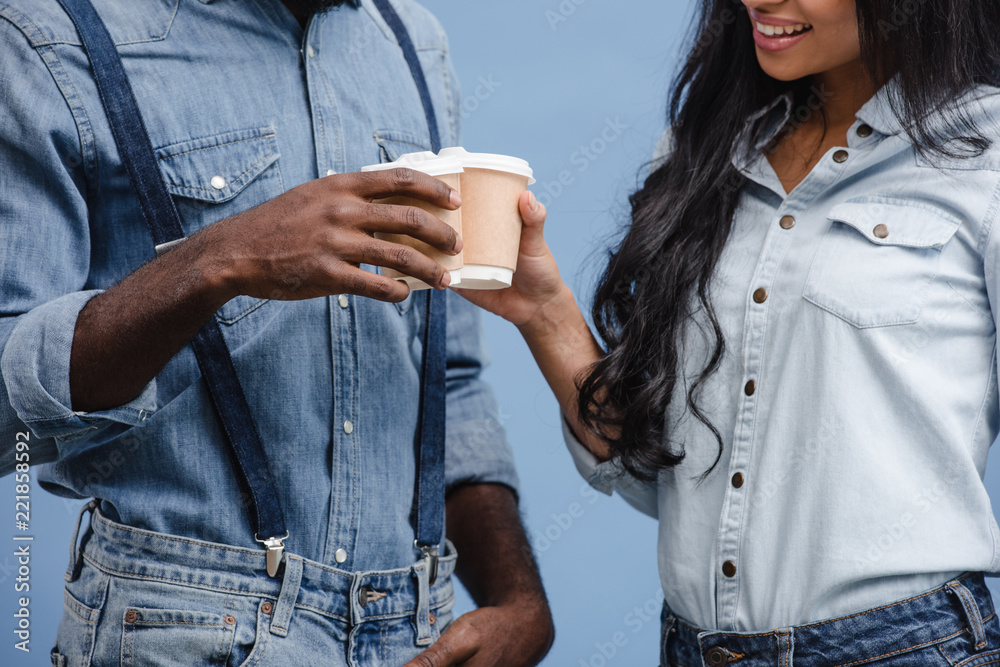 cropped image of african american couple clinking with coffee in paper cups isolated on blue cropped image of african american couple clinking with coffee in paper cups isolated on blue