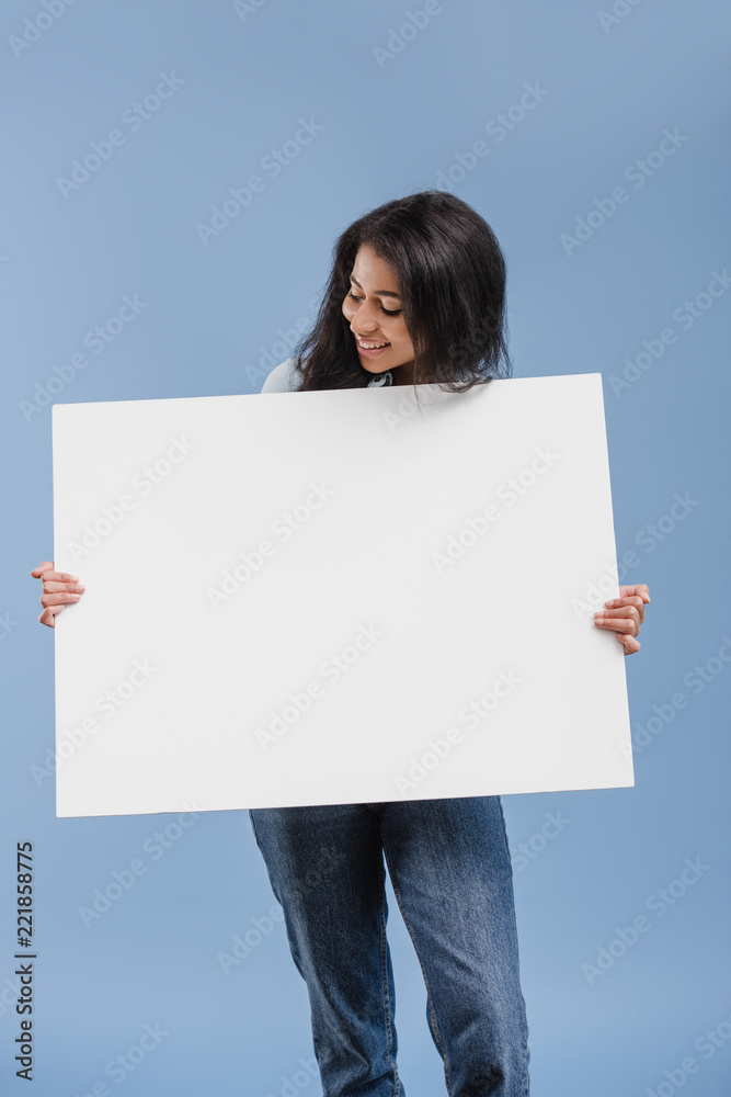 happy attractive african american girl looking at blank placard isolated on blue happy attractive african american girl looking at blank placard isolated on blue