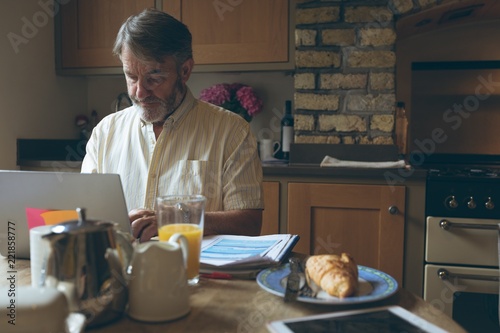 Senior man using digital tablet on dining tablet photo