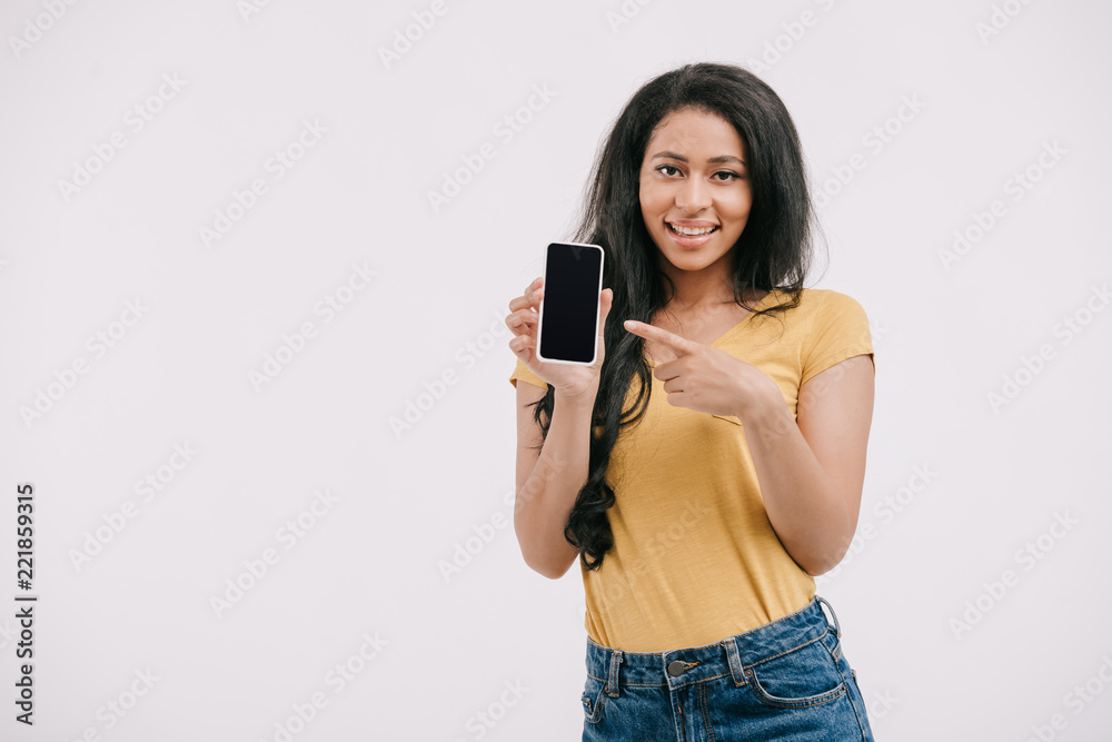 smiling african american girl pointing on smartphone with blank screen isolated on white smiling african american girl pointing on smartphone with blank screen isolated on white
