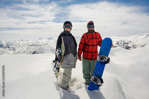 guy and a girl in ski goggles stand on the snow with snowboards
