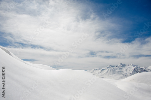 snow cover and snowy mountain peaks against the blue sky