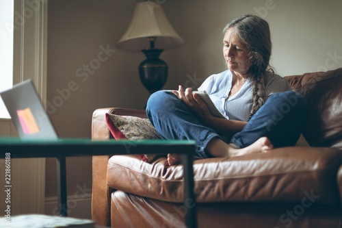 Senior woman writing on a notepad in living room photo
