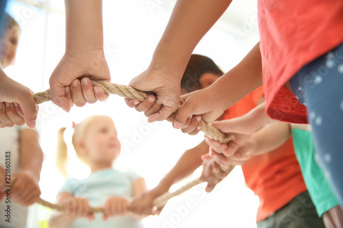 Little children holding rope on light background, focus on hands. Unity concept
