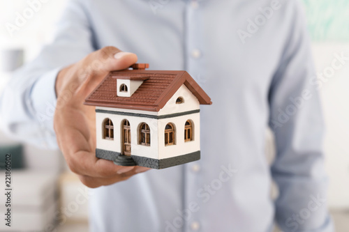 Real estate agent holding house model, closeup