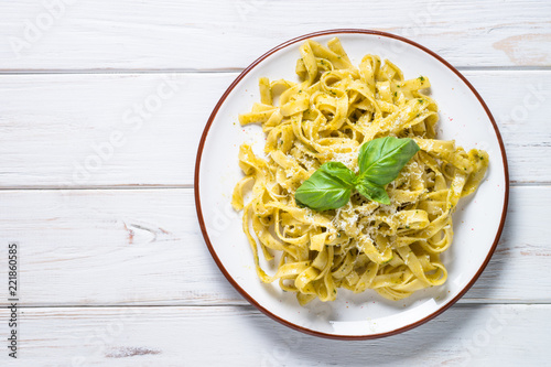 Tagliatelle pasta with pesto sauce and parmesan on white. photo