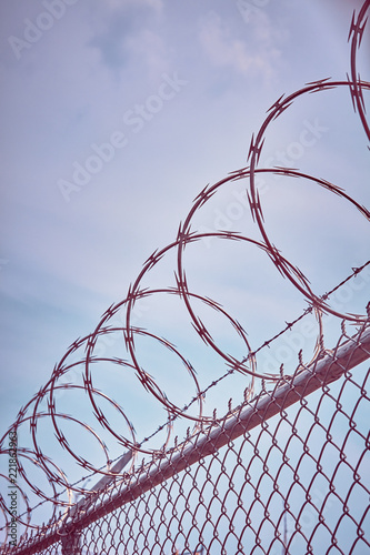 Canvas Print Color toned picture of a razor barbed wire fence against the sky, imprisonment concept, selective focus