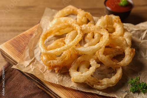 Homemade delicious golden breaded and deep fried crispy onion rings on wooden background, closeup