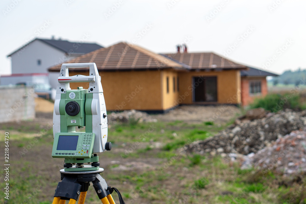 Surveyor measuring equipment (theodolit) on construction site with house in background