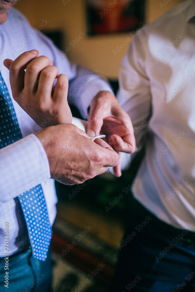 Obraz premium Groom father helping get ready for wedding. Putting wedding cufflinks on ther groom.