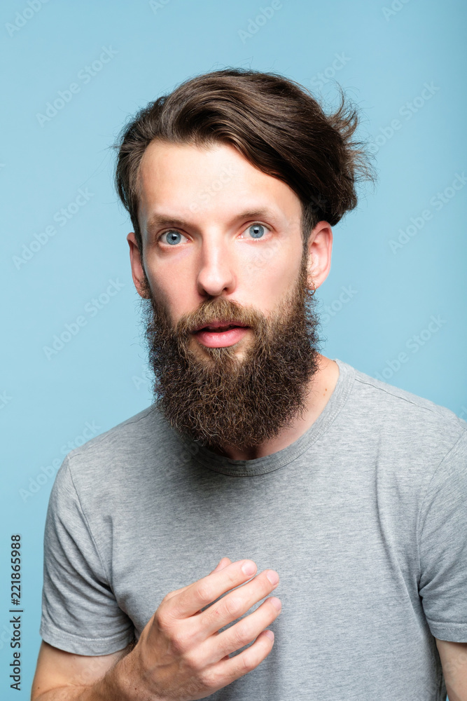 Obraz premium omg unbelievable shock. speechless dumbstruck man. portrait of a young bearded guy on blue background. emotion facial expression and reaction concept.